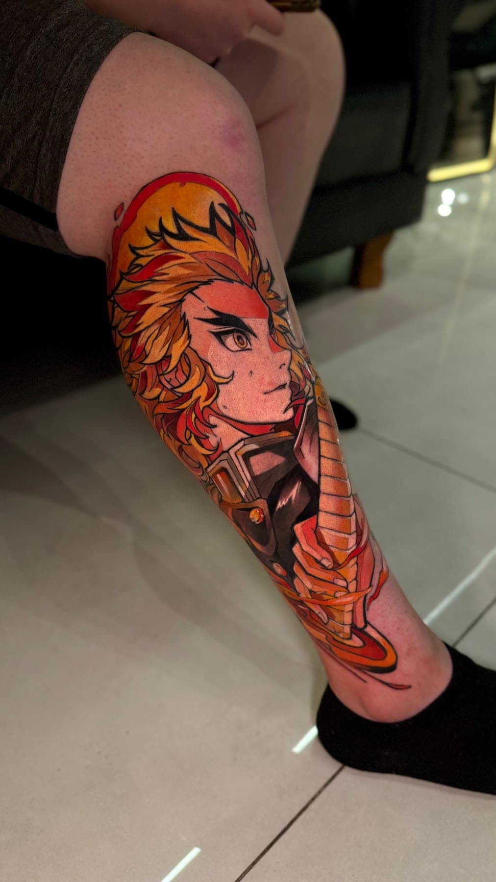 Perna em cor: personagem de cabelo laranja e chamas, com a espada descendo pela canela